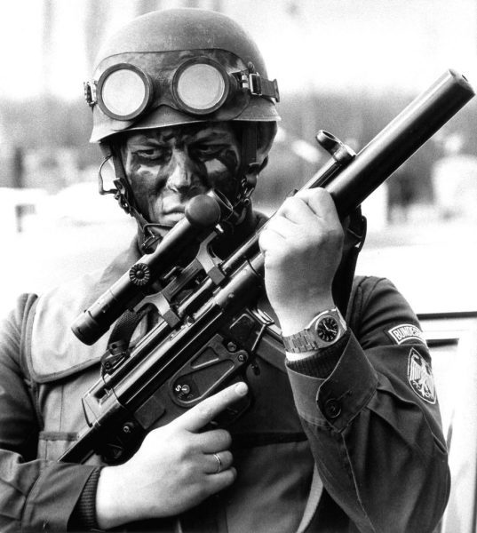 Black and white photo of a man holding a MP5SD
