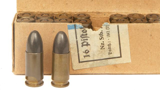Two 9 mm rounds next to an aged surplus box